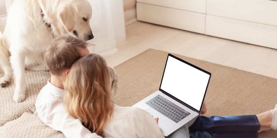 pet parents reading online guide about home dental care for pets while pet dog looks over their shoulders